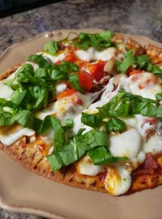 a pizza topped with cheese and veggies on top of a brown platter