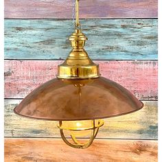 a brass colored light hanging from a wooden wall with multicolored planks in the background