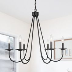 a black chandelier hanging from the ceiling in a dining room with white walls