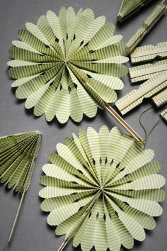 four green paper fan shaped objects on a gray surface with pins in the middle and two smaller ones attached to each other