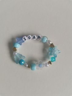 a close up of a bracelet on a white surface with beads and charms around it