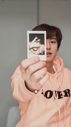 a person holding up a polaroid in front of their face