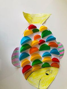 a fish made out of colored paper sitting on top of a table