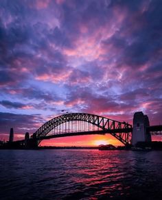 a bridge that is over some water at sunset