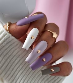 These long coffin nails boast a pastel palette of lavender, white, and grey matte shades. Each nail is adorned with a delicate gold heart accent, creating a chic and balanced design. Ideal for February nails color ideas 2025, this style combines the elegance of gel with the durability of SNS dip techniques for a classy and popular look. Nails With Gold Heart, Gold Spring Nails, French Tips Long, Spring Nails Gold, Aesthetic Nail Design, Nails For Brown Skin, Spring Nails Aesthetic, Aesthetic Spring Nails, Essence Nails