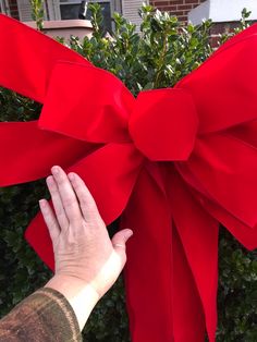 a person's hand reaching for a large red bow