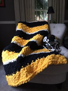 a black and yellow blanket sitting on top of a couch next to a football helmet