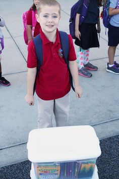 a young boy standing in front of a cooler