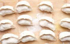 several uncooked dumplings on a wooden cutting board