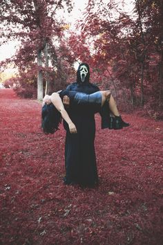 a person in a black dress and mask holding another person with their arms around each other