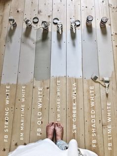 a person standing on top of a wooden floor next to different types of paint rollers