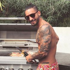 a man with tattoos on his arm grilling food