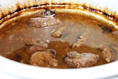 a pot filled with meat and broth sitting on top of a stove