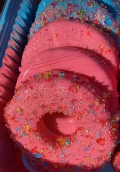 pink and blue donuts with sprinkles on them in a plastic container