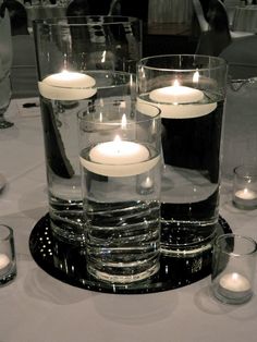 candles are lit in glass vases on a table