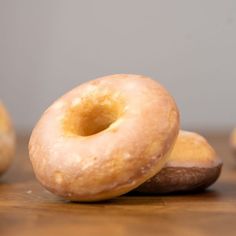 three glazed doughnuts sitting on top of a wooden table next to each other