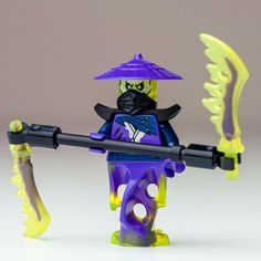 a lego man with a purple hat holding a yellow arrow and wearing a black mask