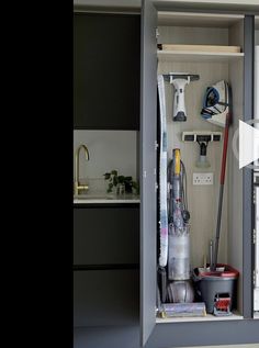 an open cabinet filled with cleaning supplies and tools