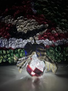 a glass ball with a bow and ribbon around it sitting in front of many rolls of yarn