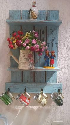 a blue shelf with flowers and cups hanging from it's sides on the wall