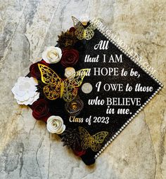 a graduation cap decorated with flowers on top of a stone floor and the words, all that i am hope to be, one to those who believe in me class of 202