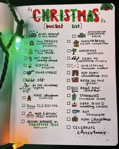 a christmas bucket list is shown in a notebook with lights on the pages and an ornament attached to it