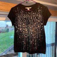 New And Never Worn Black Victoria’s Secret Tee Shirt With Gold Glitter Stars & Logo. When Laid Flat; 18” Long Down The Front, 17” Pit To Pit. Casual Glitter Top For Night Out, Glitter Crew Neck Tops For Night Out, Black Glitter Print Top For Summer, Black Glitter Print Tops For Summer, Casual Short Sleeve Glitter Tops, Trendy Black Glitter Tops, Casual Black Tops With Glitter Print, Victoria's Secret Graphic Print Crew Neck Top, Black Glitter Short Sleeve T-shirt