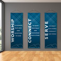 three blue banners hanging on the wall in an empty room with wood flooring and large windows