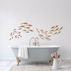 a bath tub sitting next to a white wall with gold fish decals on it