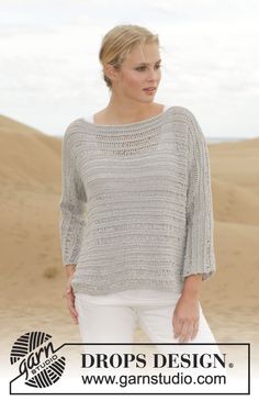 a woman standing in the sand wearing a sweater and white pants with her hands on her hips