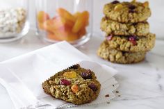 three cookies are stacked on top of each other in front of glass jars with dried fruit