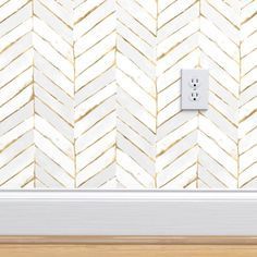 a white light switch sitting on top of a wooden floor next to a chevron wall