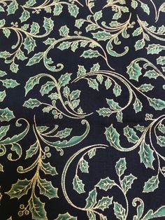 the fabric is black with green and gold designs on it's sides, as well as holly leaves