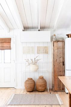 two vases sitting on top of a wooden floor next to a white refrigerator freezer