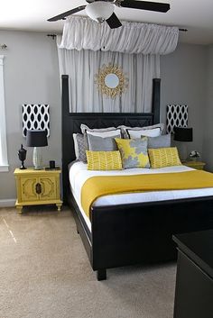 a bed with yellow and gray pillows in a bedroom