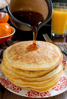 pancakes on a plate with syrup being poured onto them