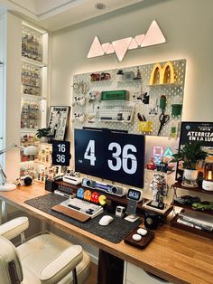 a computer desk with a clock on the wall above it and several other items around it