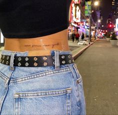 a woman's stomach with a small tattoo on her left side, in the middle of a city street at night