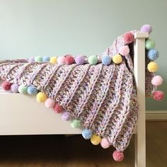 a crocheted blanket with pom - poms on it