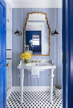 a white sink sitting under a mirror next to a blue door in a room with black and white checkered walls