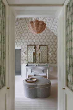 a bathroom with two sinks and mirrors on the wall, along with a round ottoman