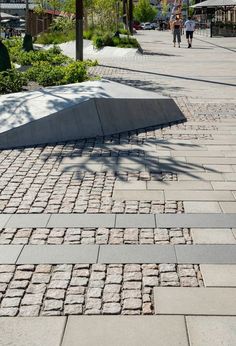 a person walking down a sidewalk with a skateboard in the foreground and people walking on the other side