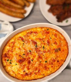 an omelet in a white dish on a table with other plates and utensils