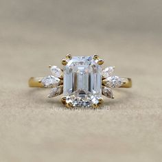 an emerald cut diamond ring with three pear shaped diamonds on the band and side stones