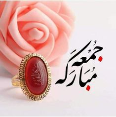 a ring with an arabic calligraphy on it and a pink rose in the background