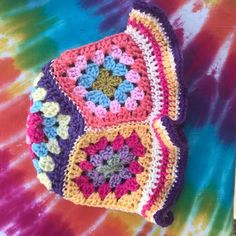 a multicolored crocheted purse sitting on top of a tie dyed table