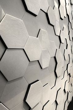 an abstract wall made up of hexagonal tiles in white and grey tones with black accents