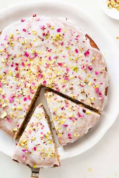 a cake with white frosting and sprinkles on it sitting on a plate