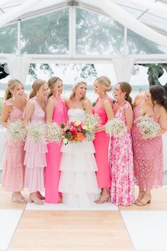 a group of women standing next to each other in front of a white and pink tent