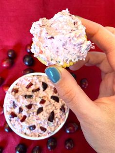 a hand holding a cupcake with frosting and chocolate chips on it next to an oatmeal